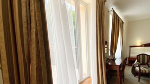 Een hotelkamer met een groot raam, een houten bankje, een eettafel en een stoel.