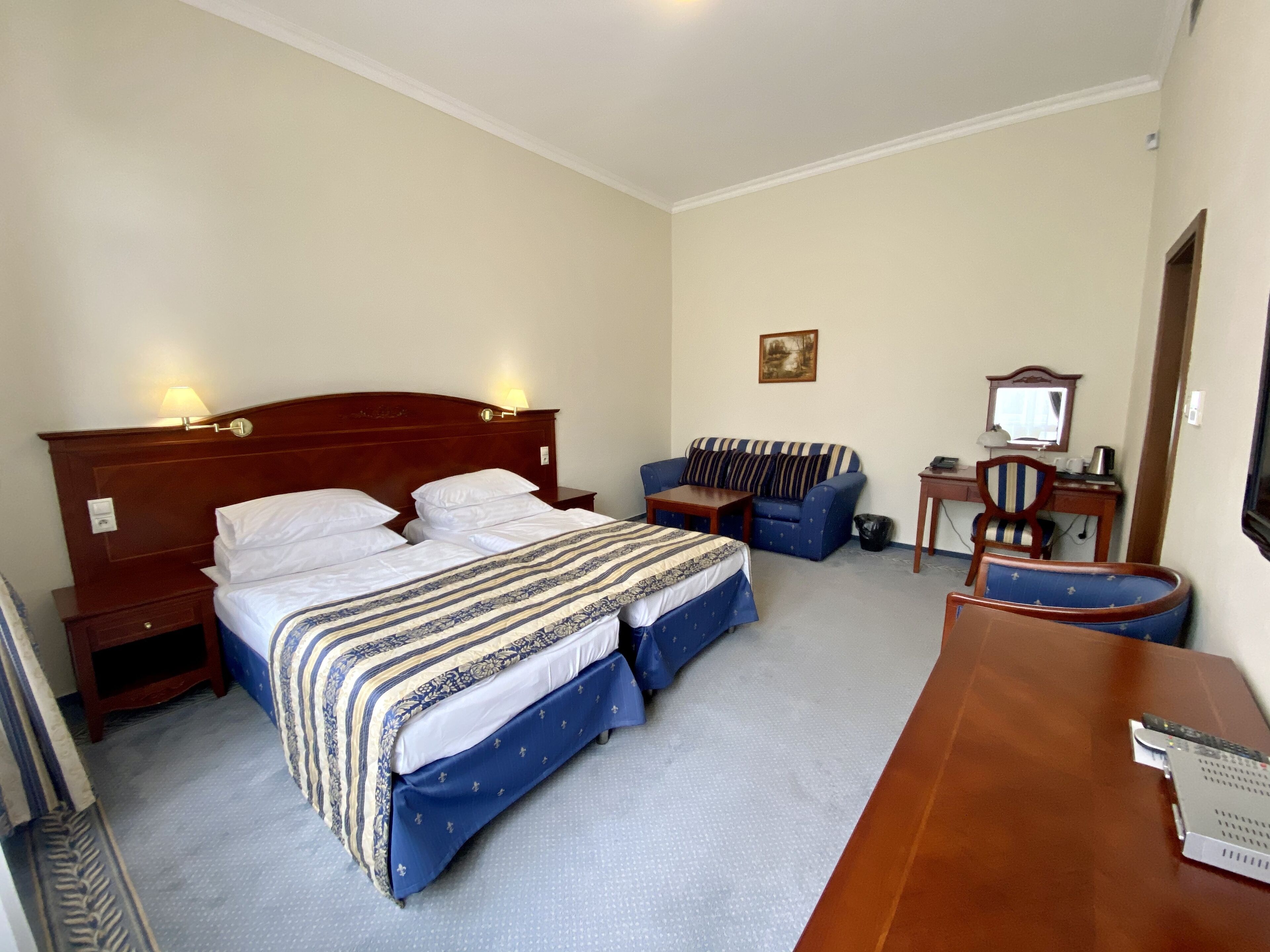 Een hotelkamer met een tweepersoonsbed, een slaapbank, een bureau met stoel en een kleine tafel.