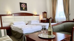 Een hotelkamer met twee bedden, een eettafel met een fles champagne en een stoel.