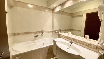 A bathroom with two sinks, a bathtub, and a large mirror.