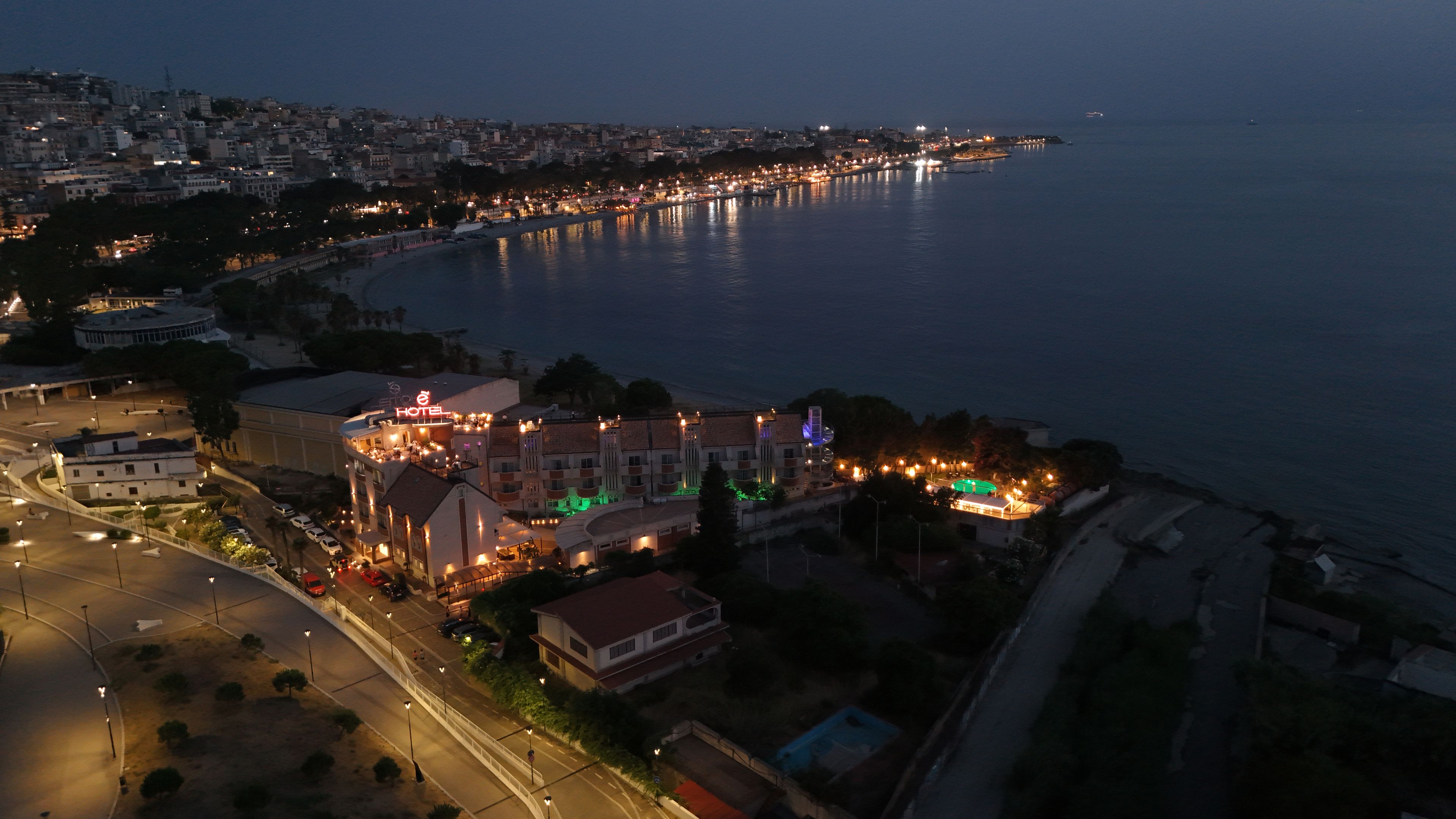 A coastal hotel with multiple buildings, a marina, and a road leading to the waterfront.