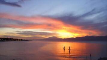 Un tramonto su acque calme con due barche a vela.