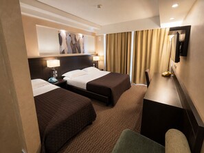 A hotel room with two beds, a desk, a chair, a telephone, and a painting on the wall. - èHotel (Reggio Calabria)
