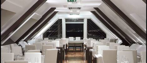 A restaurant with a high ceiling and a view of the city at night.