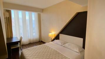 Ein Hotelzimmer mit Bett, Schreibtisch, Stuhl und Lampe.