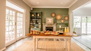 Een eethoek met een gedekte tafel, een open haard en een groene wand met decoratieve borden.