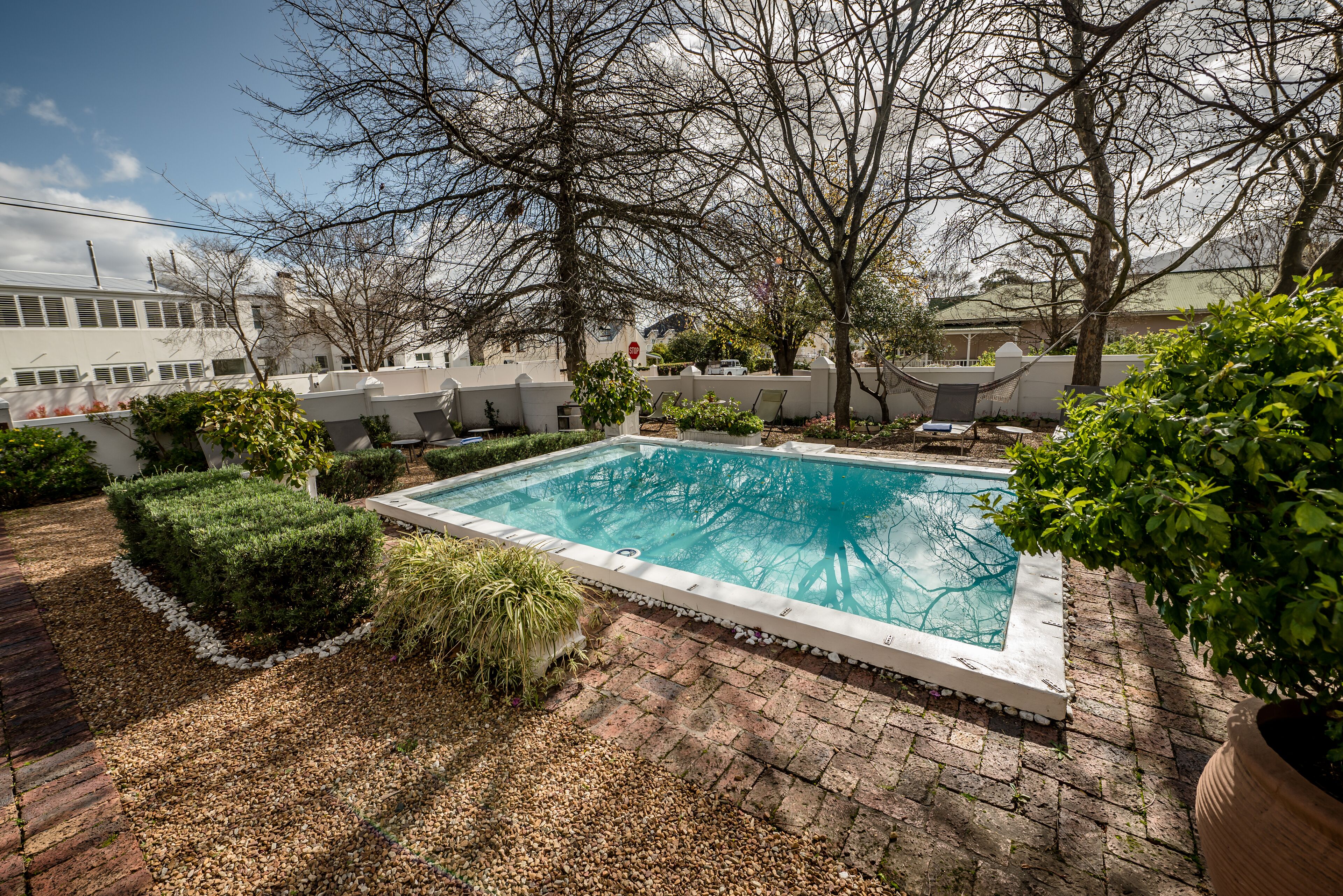 Una piscina al aire libre, sombrillas, sillones reclinables de piscina