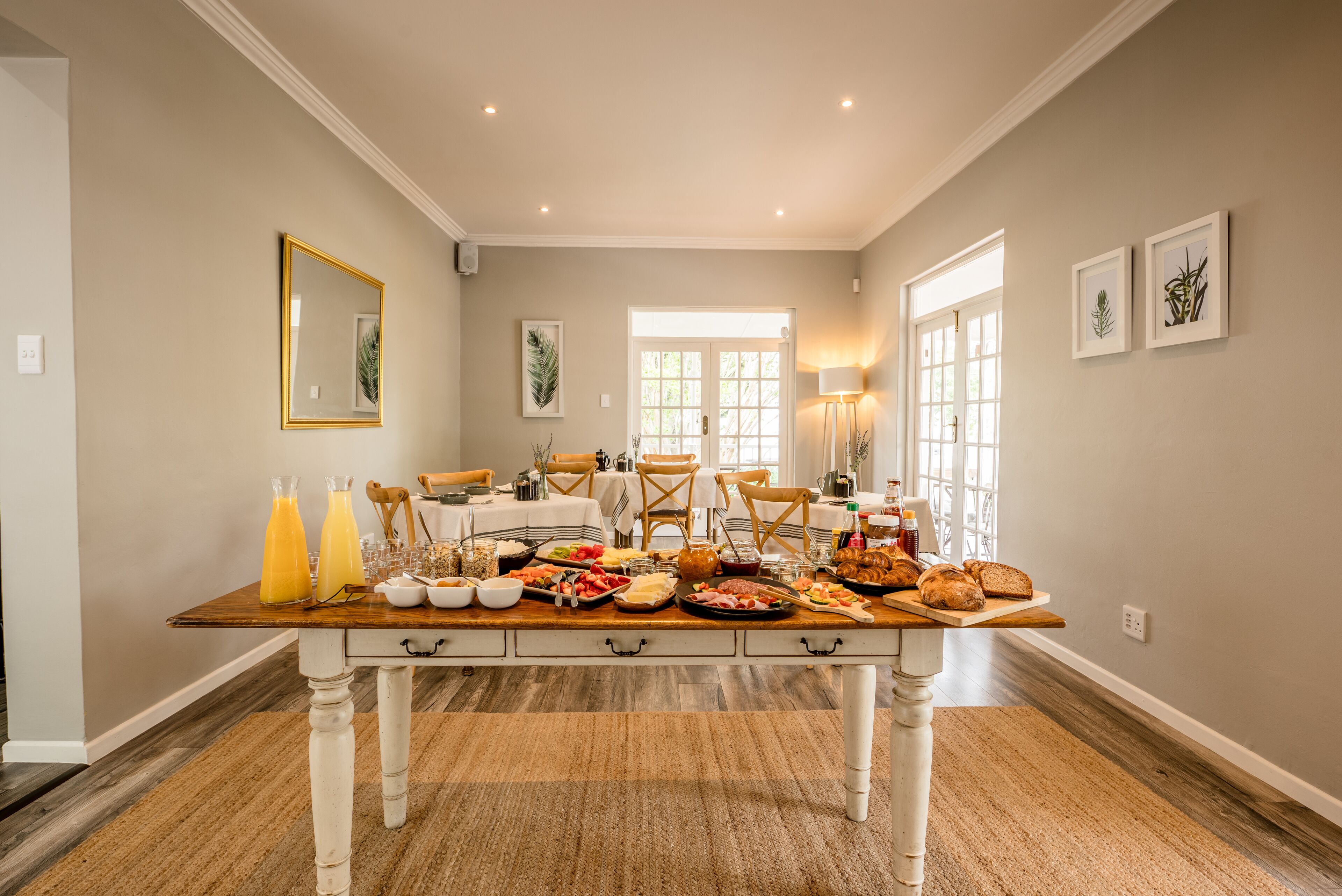 Uma sala de jantar com uma longa mesa de madeira posta para uma refeição, cercada por cadeiras.
