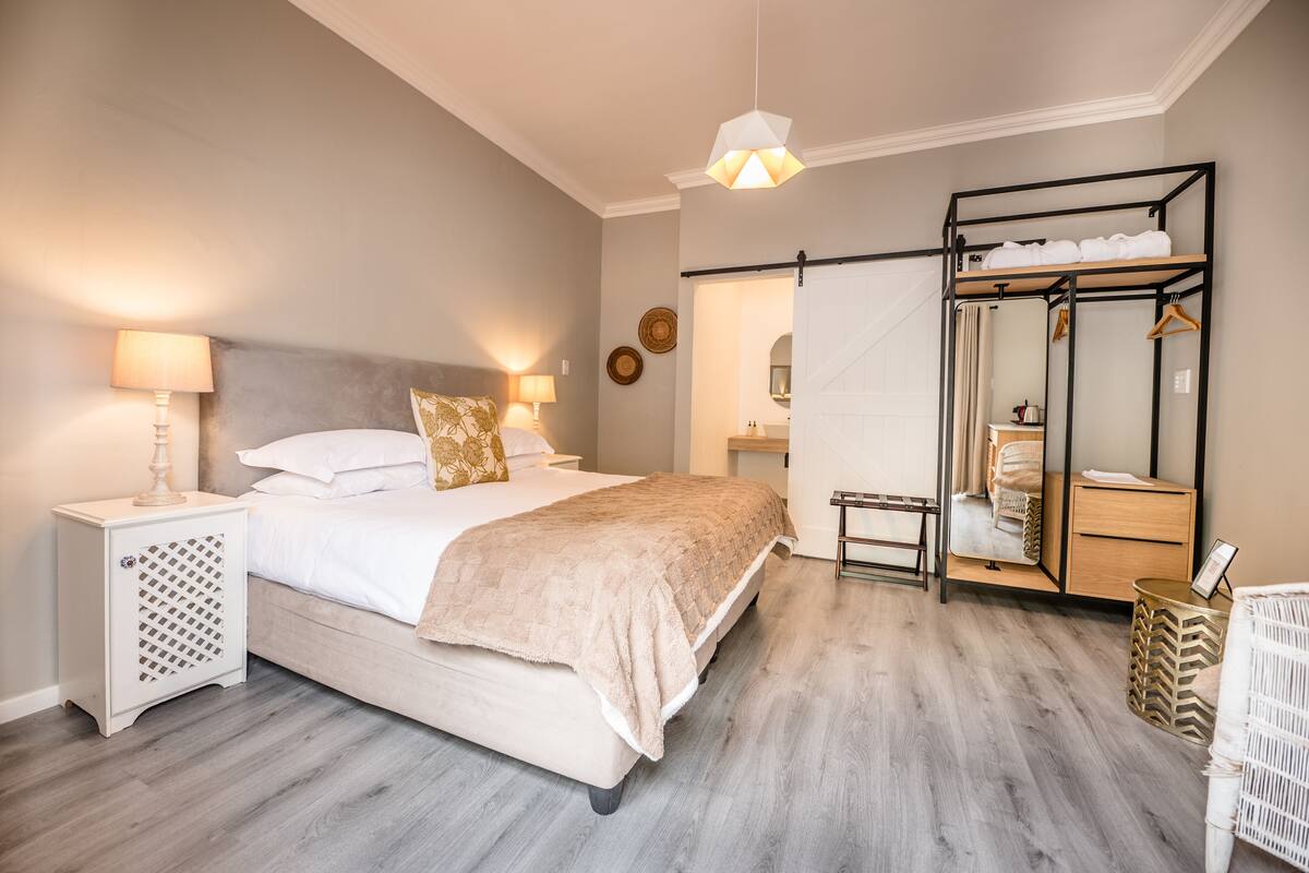 A bedroom with a bed, bedside tables, a mirror, a wardrobe, and a hanging light fixture.