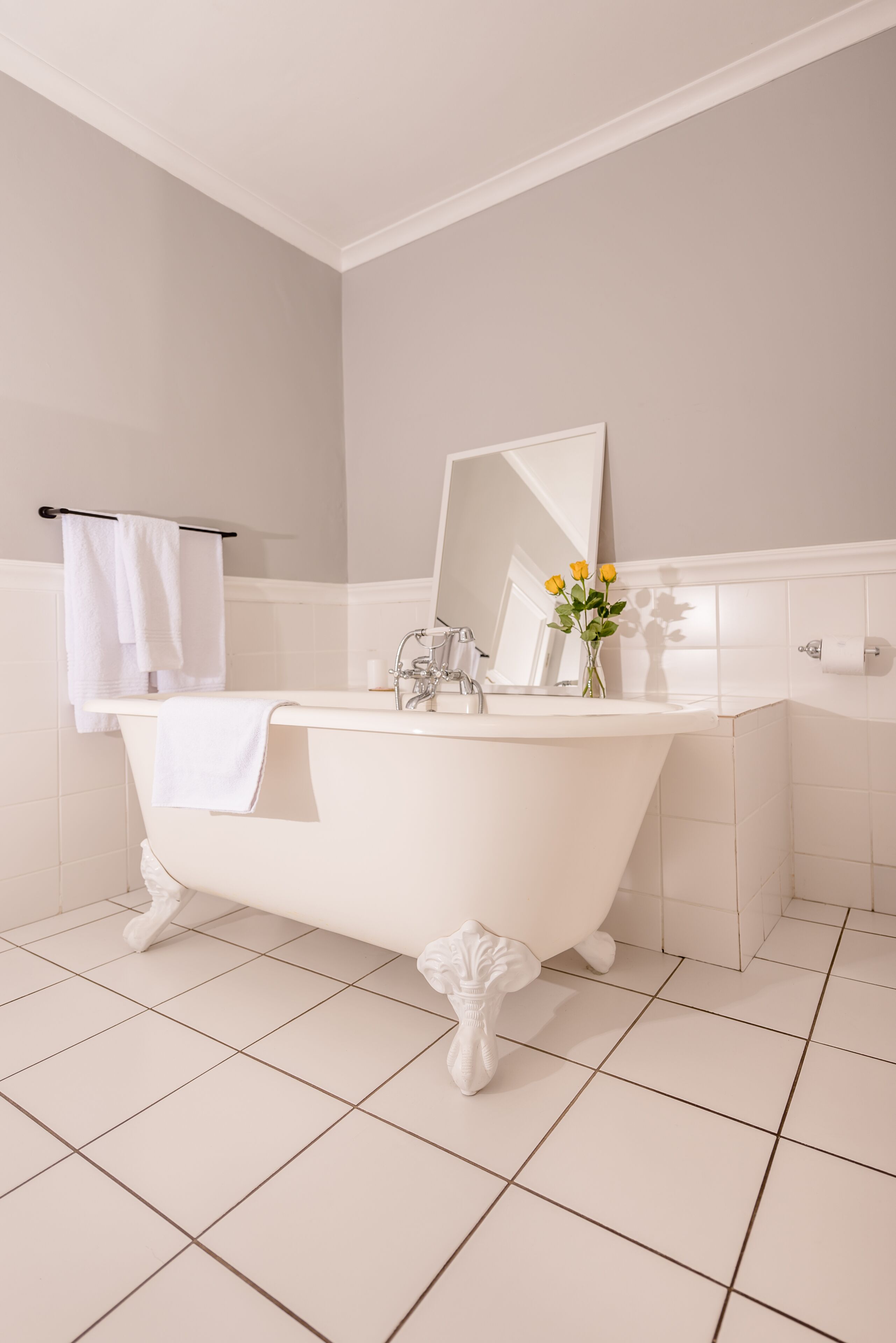 Un baño con una bañera independiente, un espejo, un lavabo y un perchero para toallas.