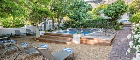 A pool area with lounge chairs and a wooden deck.