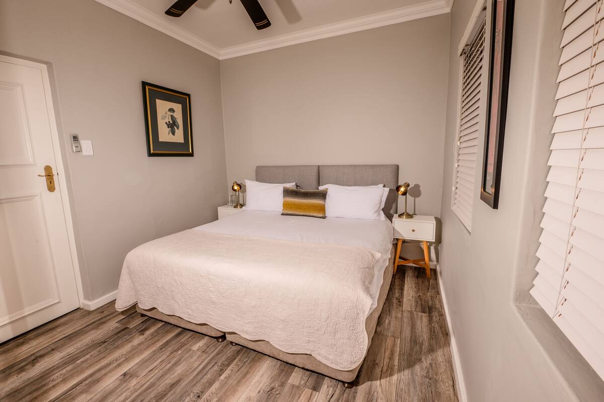 A bedroom with a large bed, bedside tables, a framed picture on the wall, and a door.