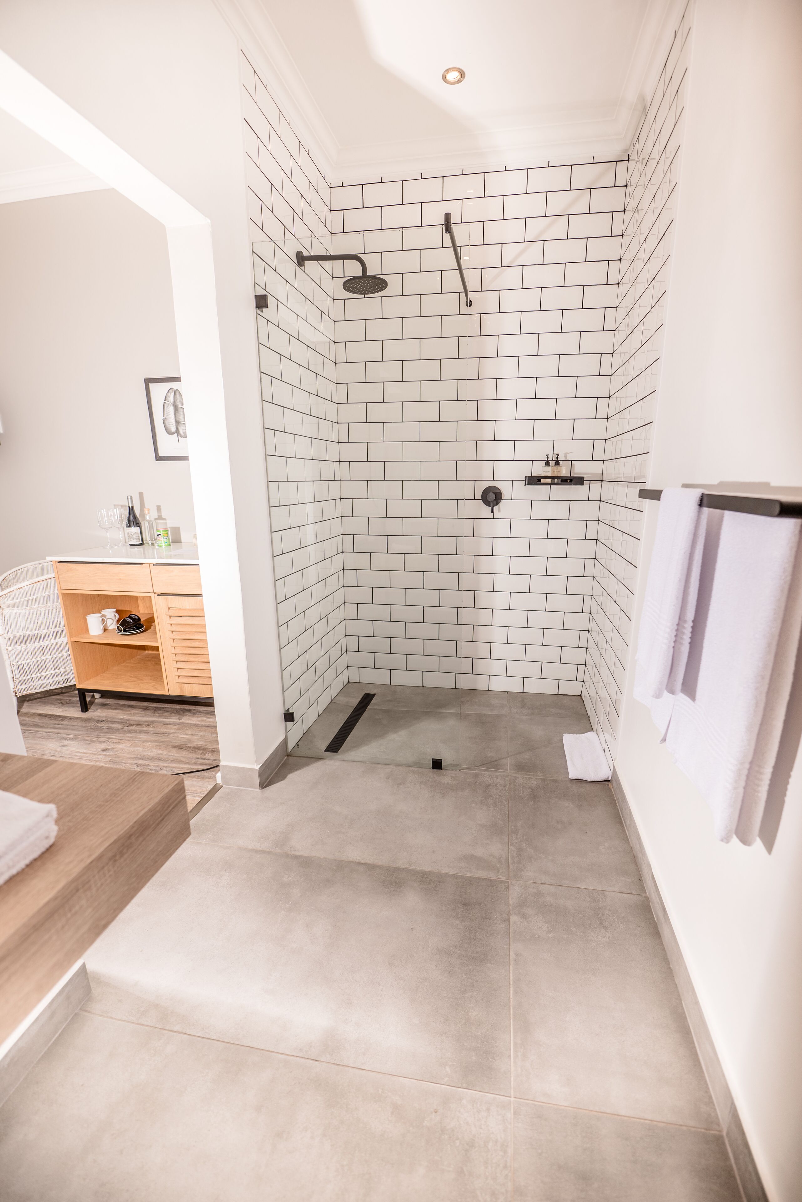 Un bany modern amb dutxa, parets de rajola i un moble de tocador de fusta amb un lavabo.