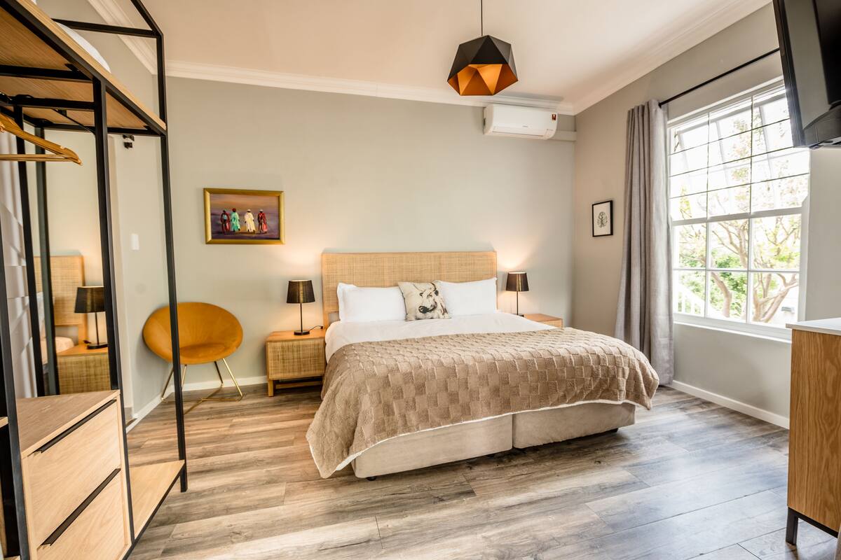 A bedroom with a bed, bedside tables, a chair, a wardrobe, and a window with curtains.