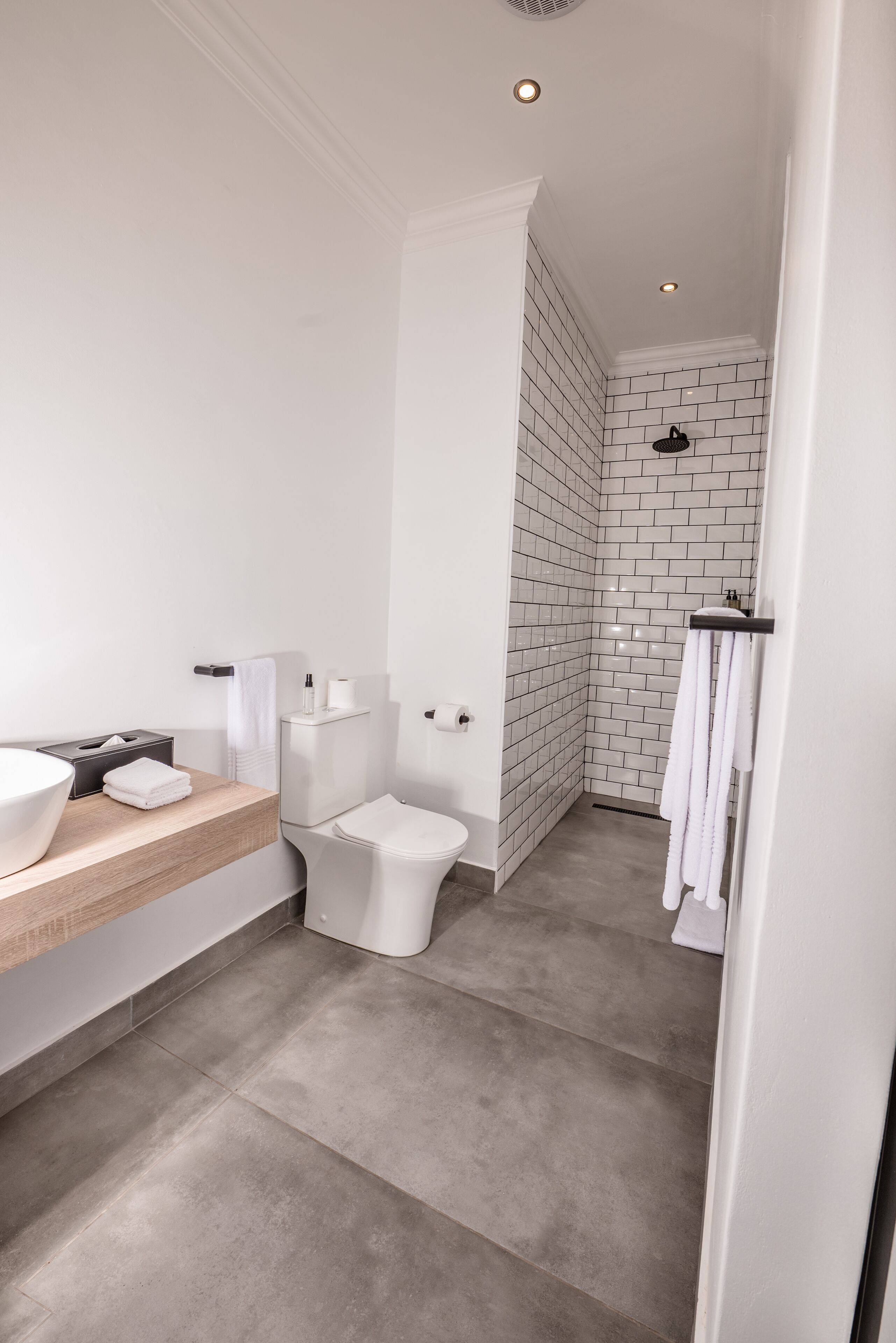 Et moderne badeværelse med hvid vask, toilet og brusebad.