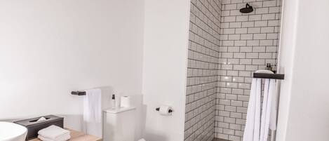 Et moderne badeværelse med hvid vask, toilet og brusebad.