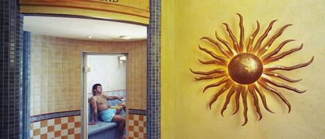 A sun mural and a sign reading "DUSCHEN DAMPFBAD" in a bathroom with checkered tile walls.