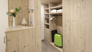 Una habitación con paneles de madera, un escritorio pequeño, una maleta verde y un perchero.