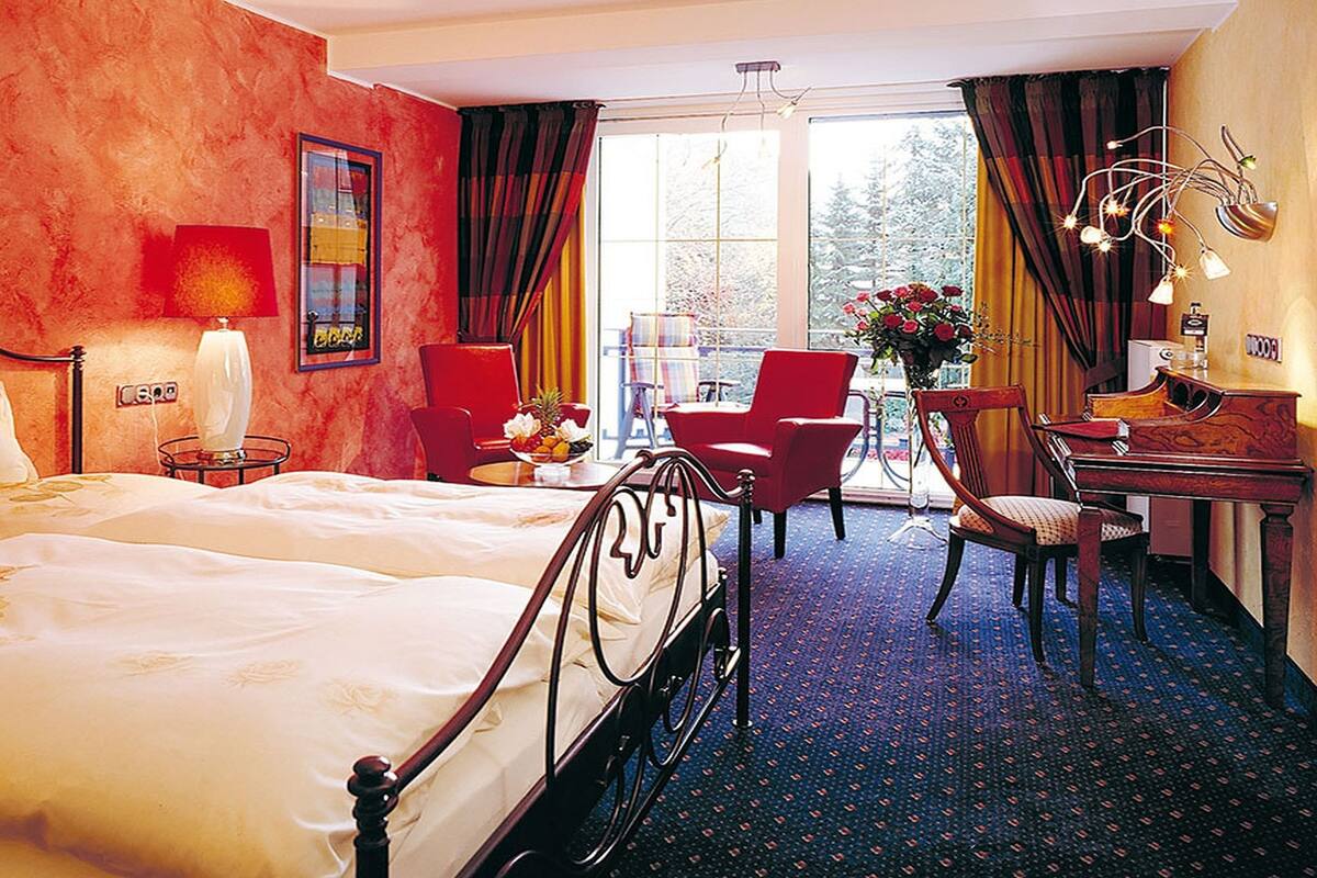A hotel room with a large bed, a desk, a chair, and a view of the outdoors.