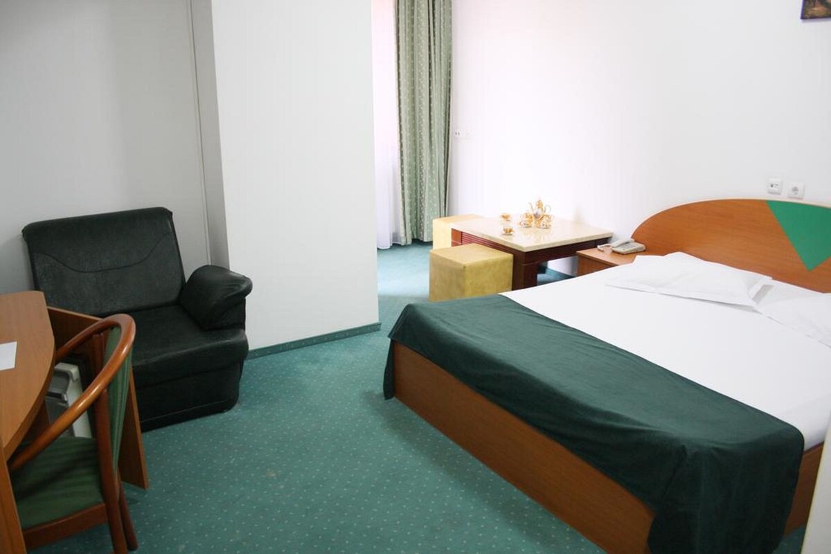 Hotellihuone, jossa on sänky, työpöytä, tuoli ja sohva.