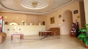 Un hall con mostrador de recepción, zona de estar y techo decorativo.