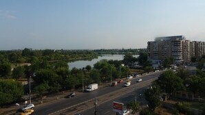 Un edificio de varios niveles con vistas a un río y una calle con mucho tráfico.