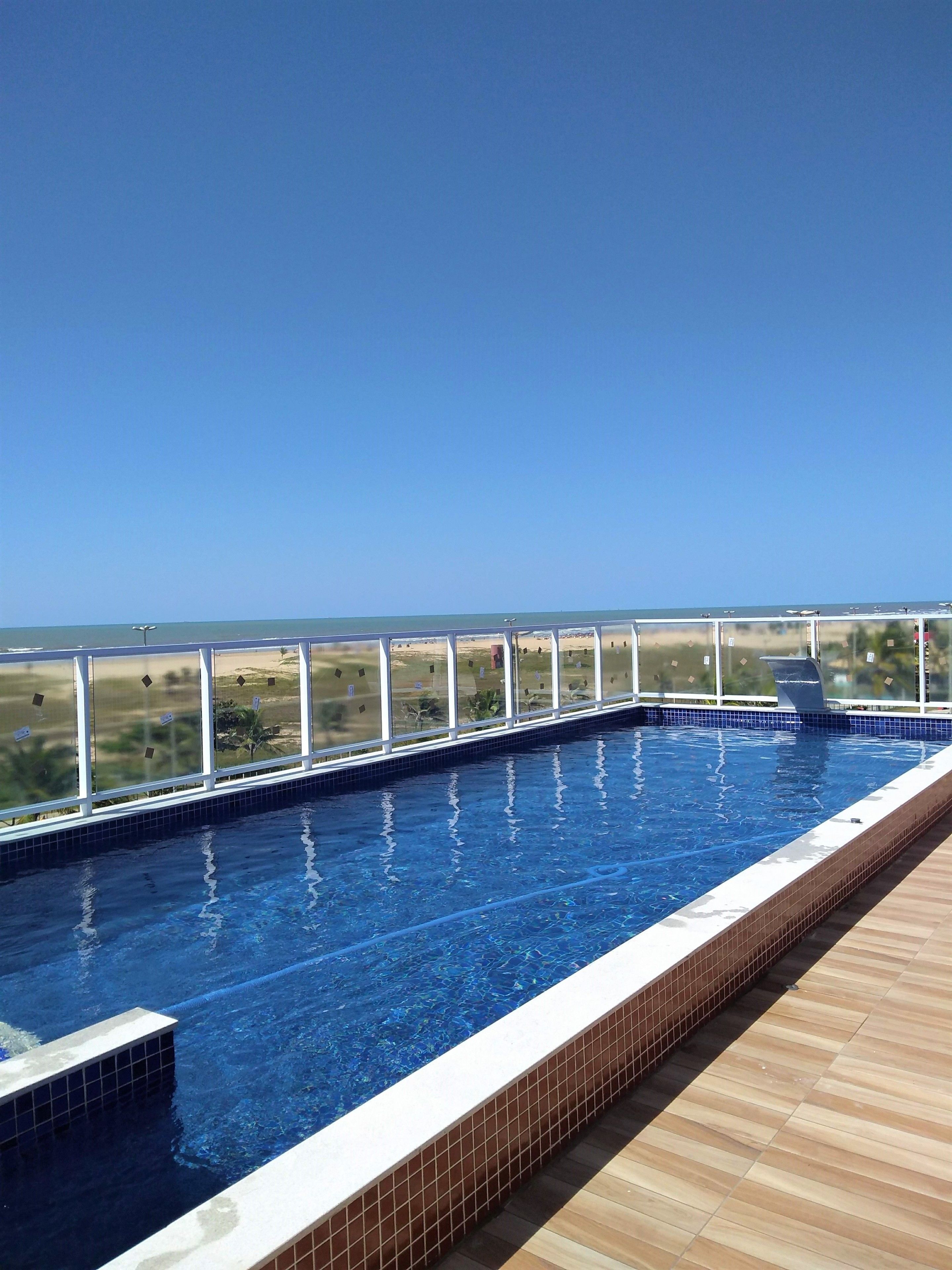 Una piscina en la azotea con vistas despejadas al océano y al paisaje distante.