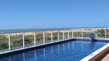 Una piscina en la azotea con vistas despejadas al océano y al paisaje distante.
