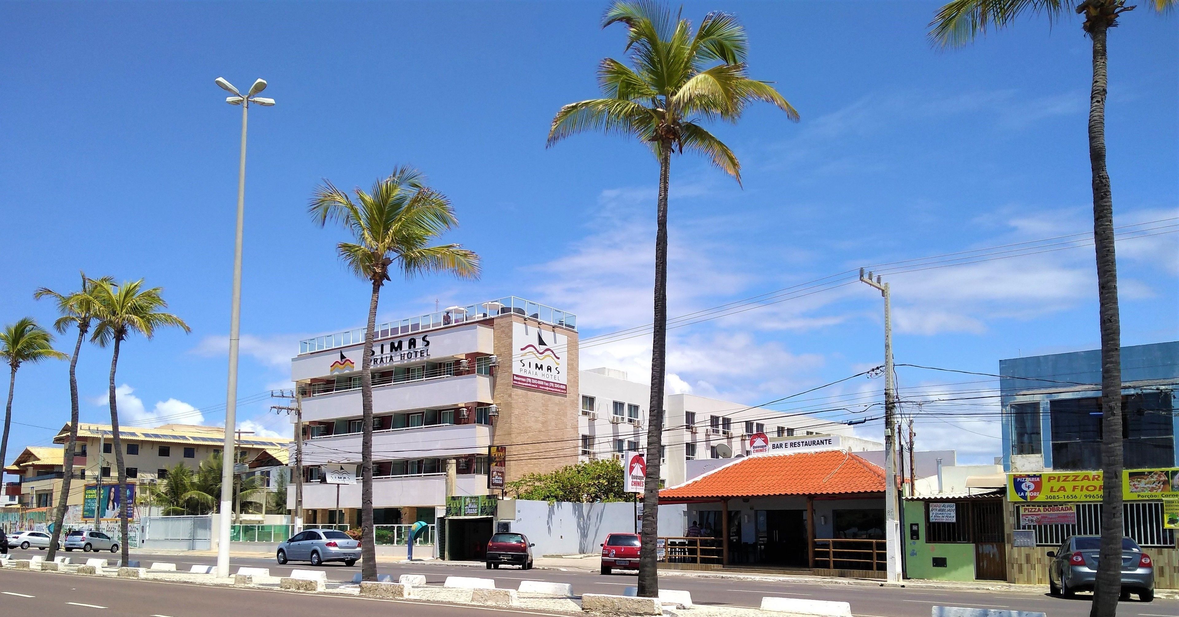 A hotel with a sign reading "SIMAS PRATA HOTEL" and a restaurant named "SIMAS PRATA HOTEL BAR E RESTAURANTE" with a red-tiled roof.