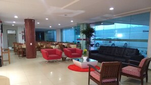 A spacious lobby with a seating area, a coffee table, and a large window offering a view of the outside. - Simas Praia Hotel (Aracaju)