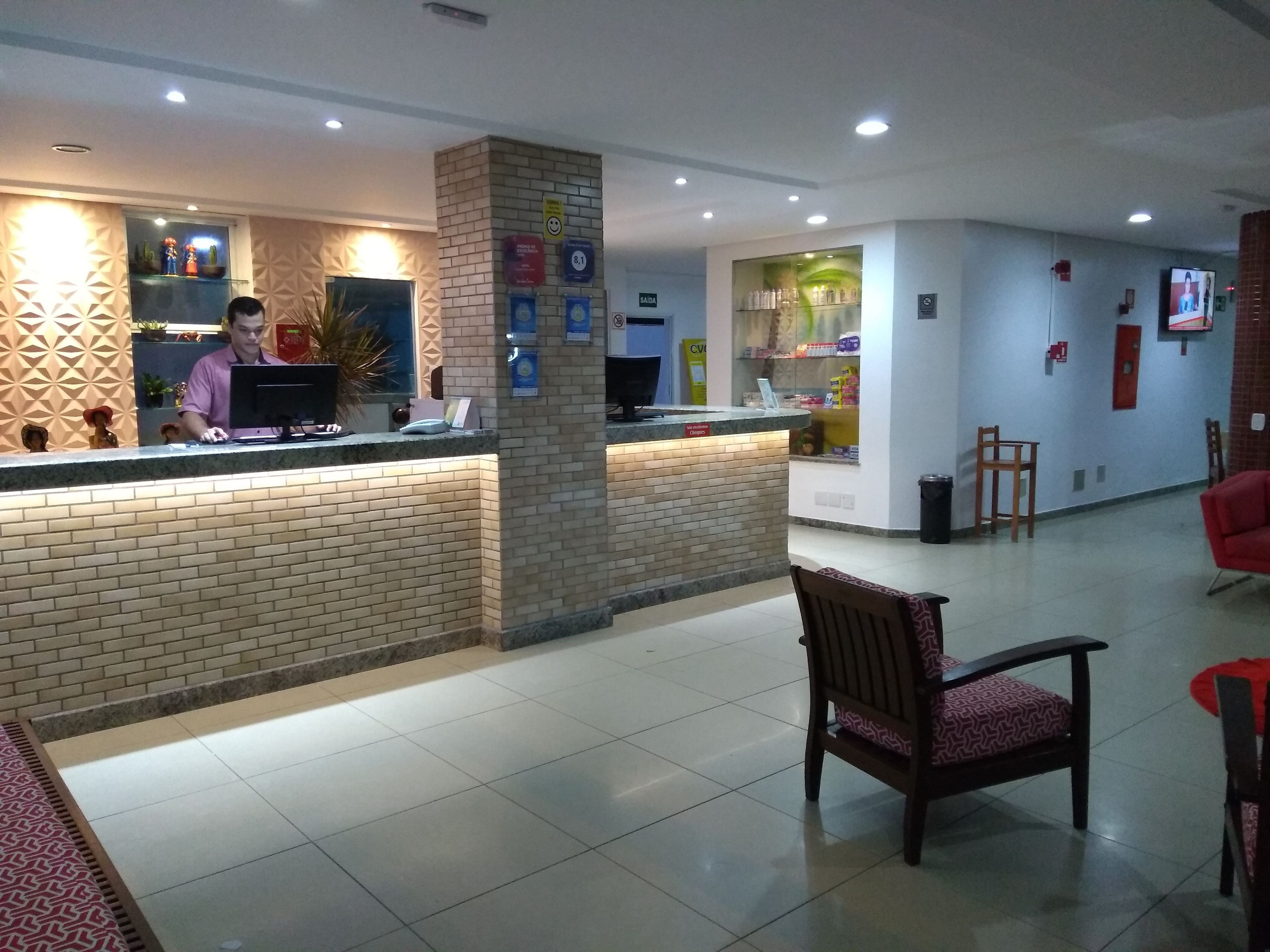 A reception area with a counter, a computer, and a seating area with chairs.