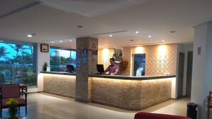 A hotel reception area with a brick counter, a clock, and a sign indicating 'Apartamentos'. - Simas Praia Hotel (Aracaju)