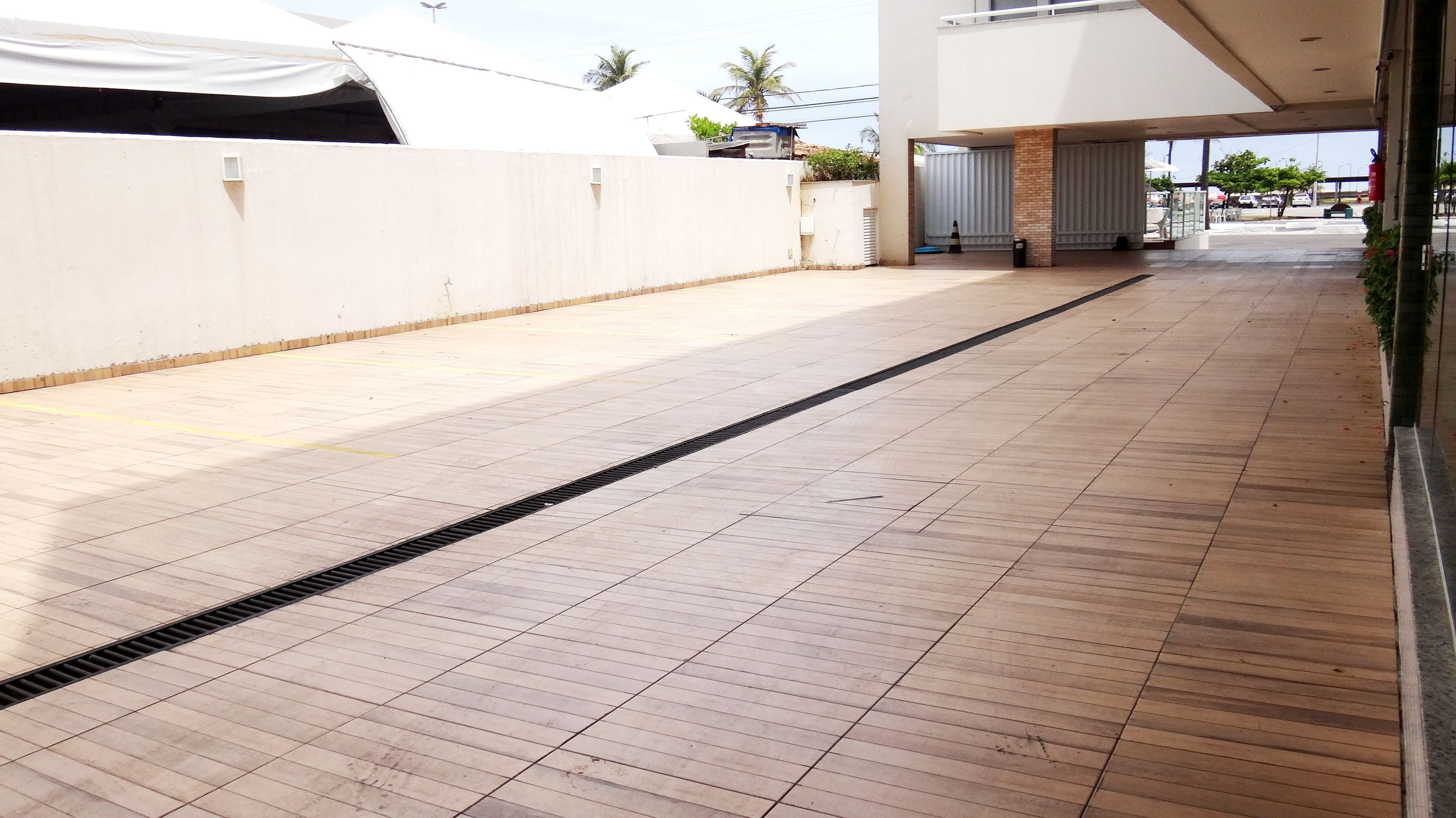 Un trottoir carrelé et bien entretenu, équipé d’une grille d’évacuation, menant à l’entrée d’un bâtiment.