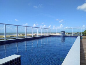 A rooftop infinity pool with a clear view of the beach and ocean.