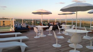A rooftop terrace with white furniture, including sofas and tables, and umbrellas providing shade. - Simas Praia Hotel (Aracaju)