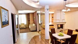 A modern hotel room with a dining area, a living room, and a fireplace. - Hotel Olsi (Chisinau)