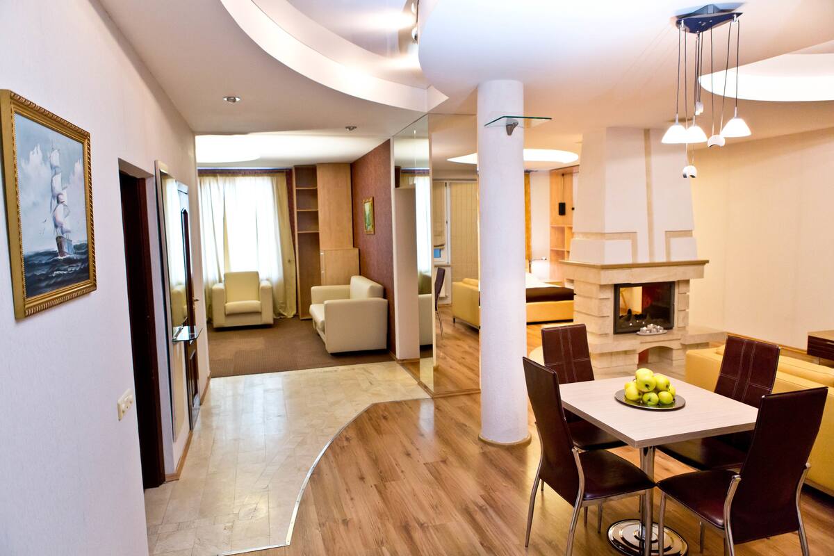 A modern hotel room with a dining area, a living room, and a fireplace.