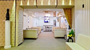 A hotel lobby with a central seating area, a reception desk, and a television screen. - Hotel Olsi (Chisinau)