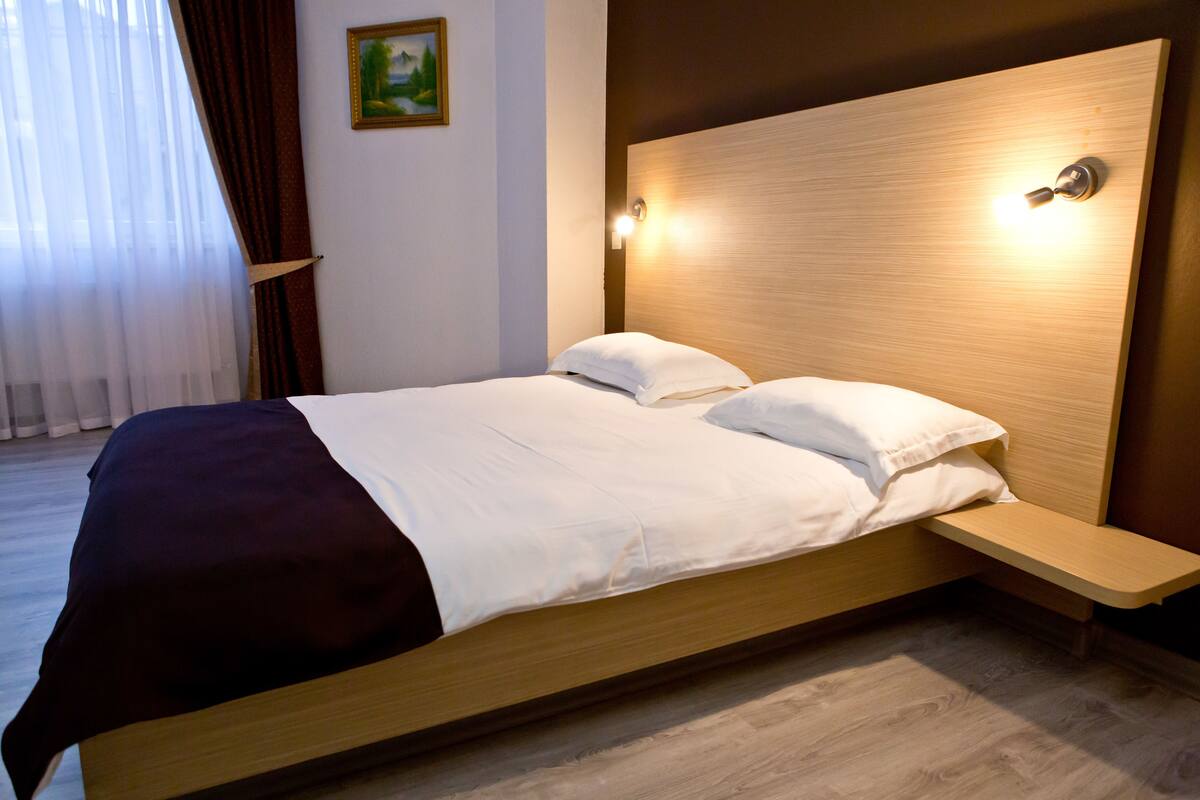 A modern bedroom with a wooden bed, white bedding, and a nightstand.