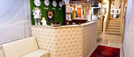 Een receptiezone met een stoffe bekleden balie, klokken en een kerstboom.
