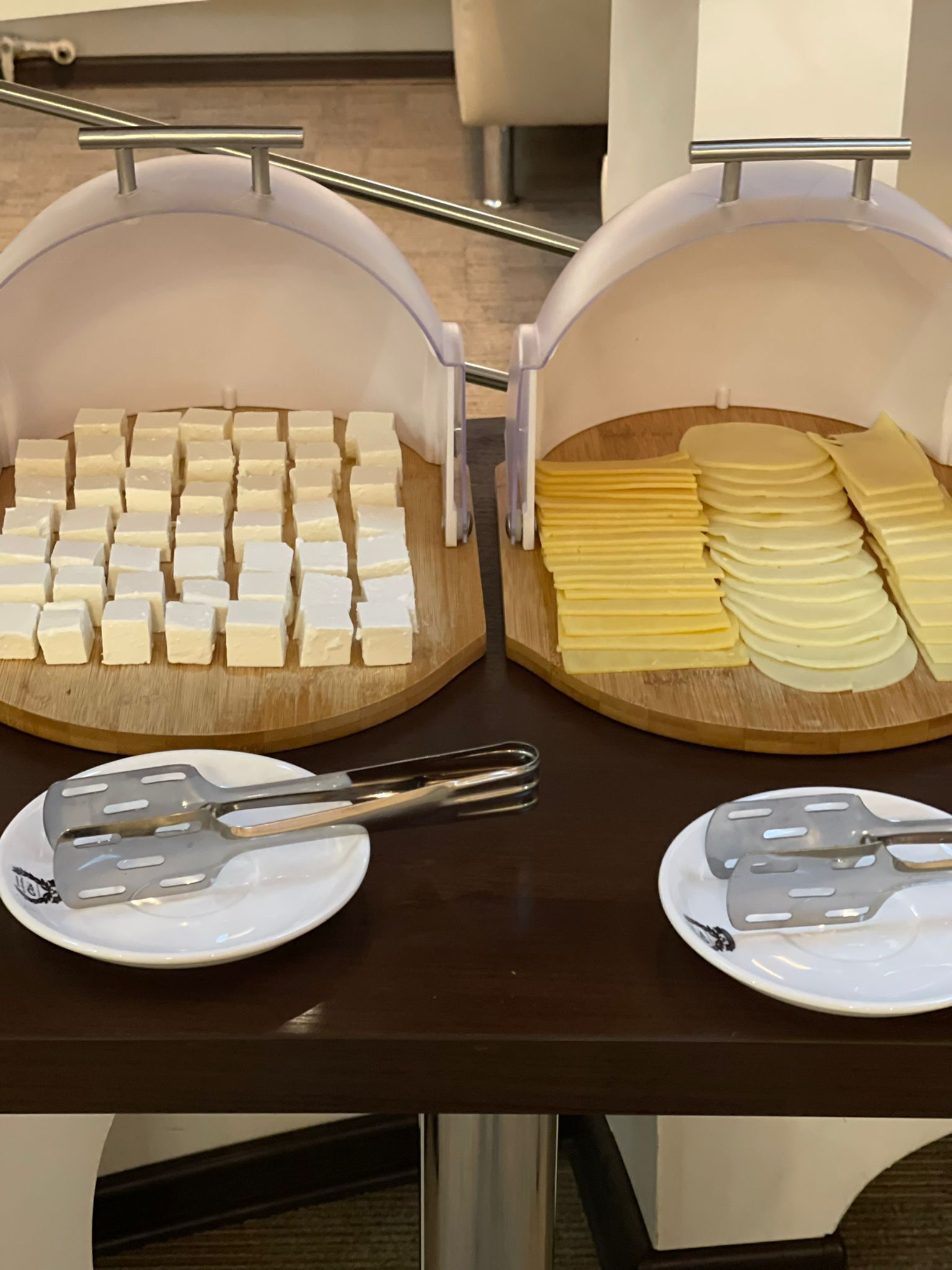 Dos bandejas de queso sobre una tabla de madera, con pinzas sobre los platos.