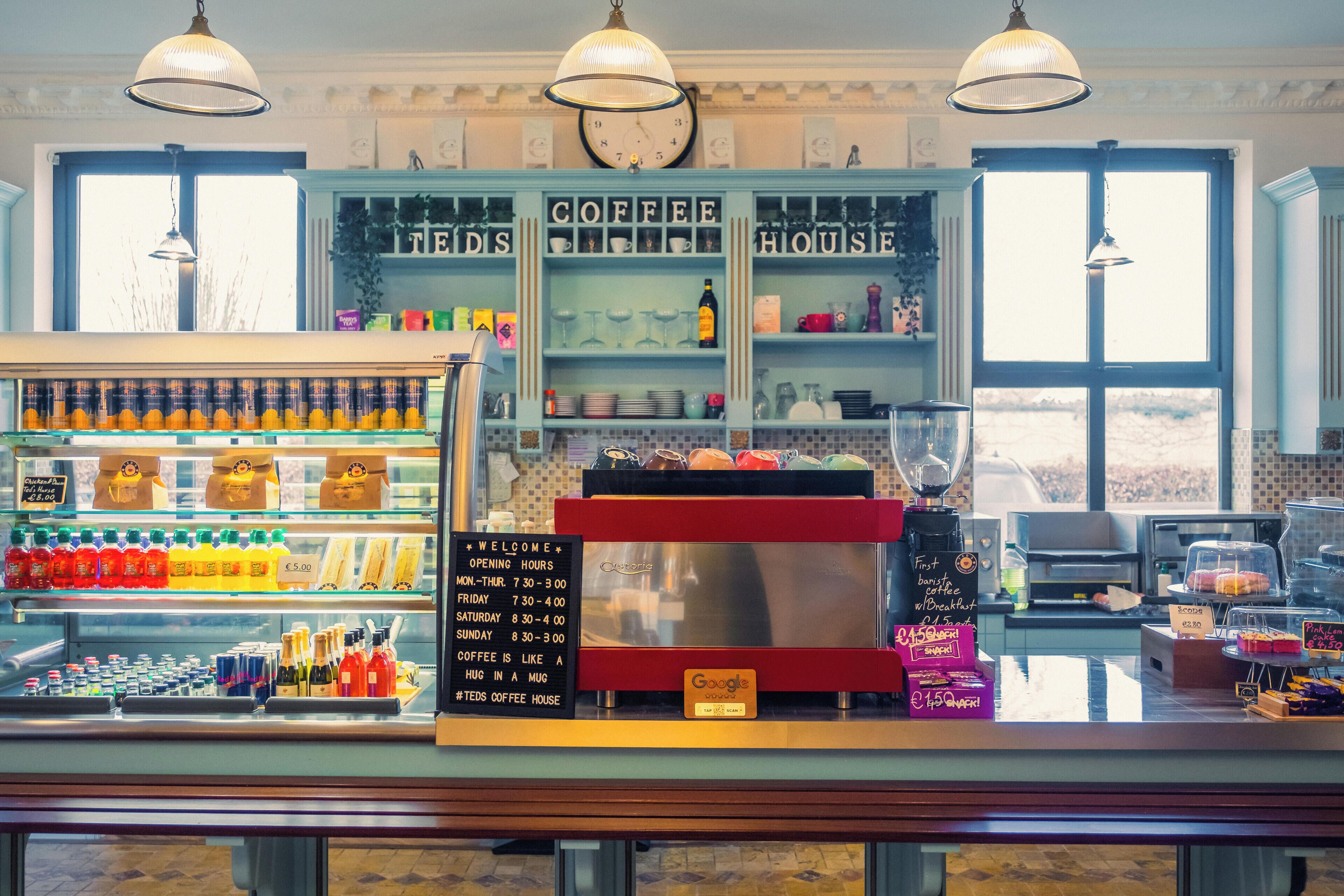 A coffee shop interior with a counter displaying various beverages and a menu board.