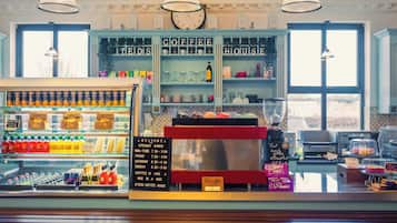 A coffee shop interior with a counter displaying various beverages and a menu board.