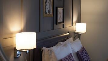 Una habitación de hotel con una cama, dos lámparas de pared y obras de arte enmarcadas.