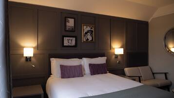 A hotel room with a large bed, two bedside tables, a chair, and wall-mounted lamps.