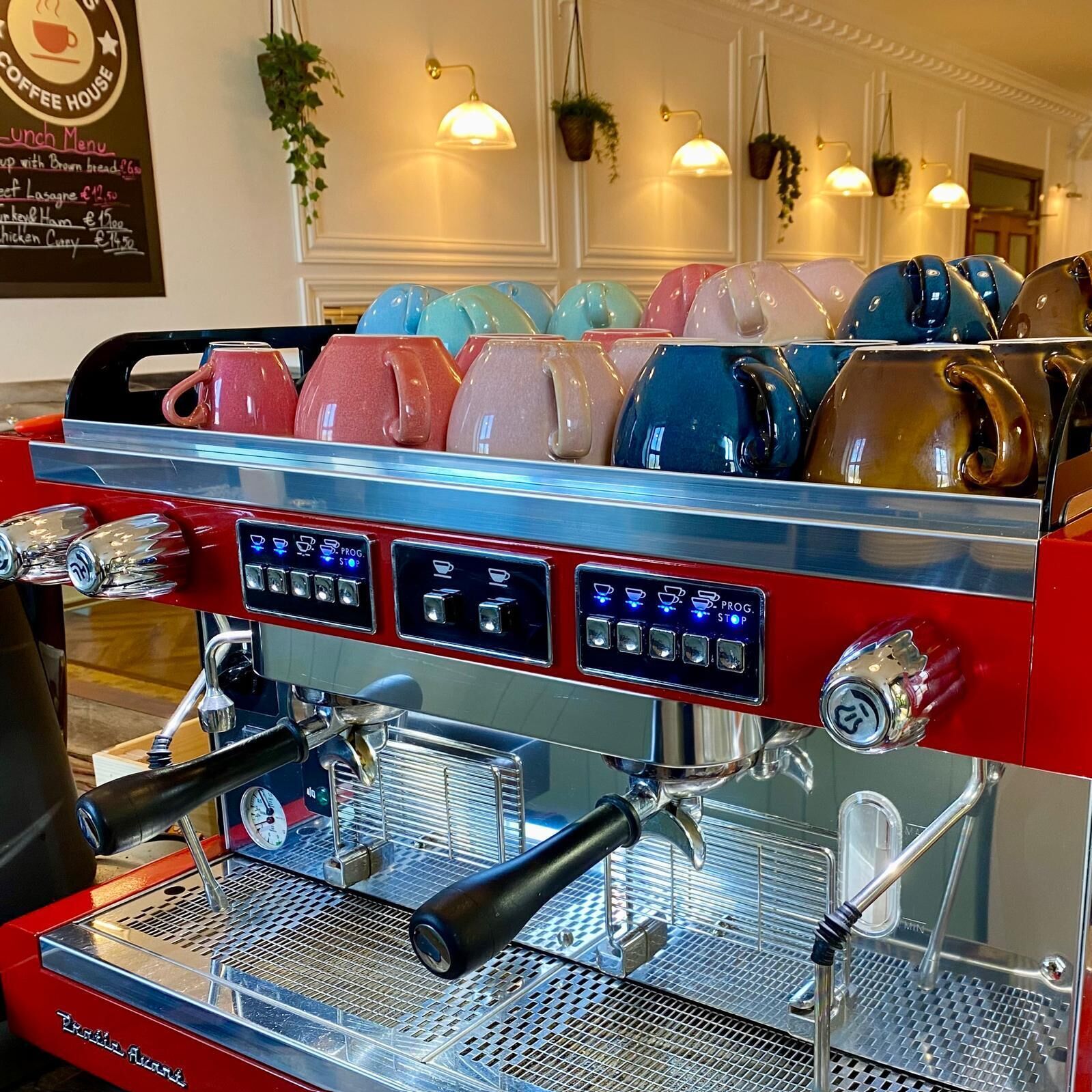A coffee machine with multiple drink options and a menu board in a cafe.