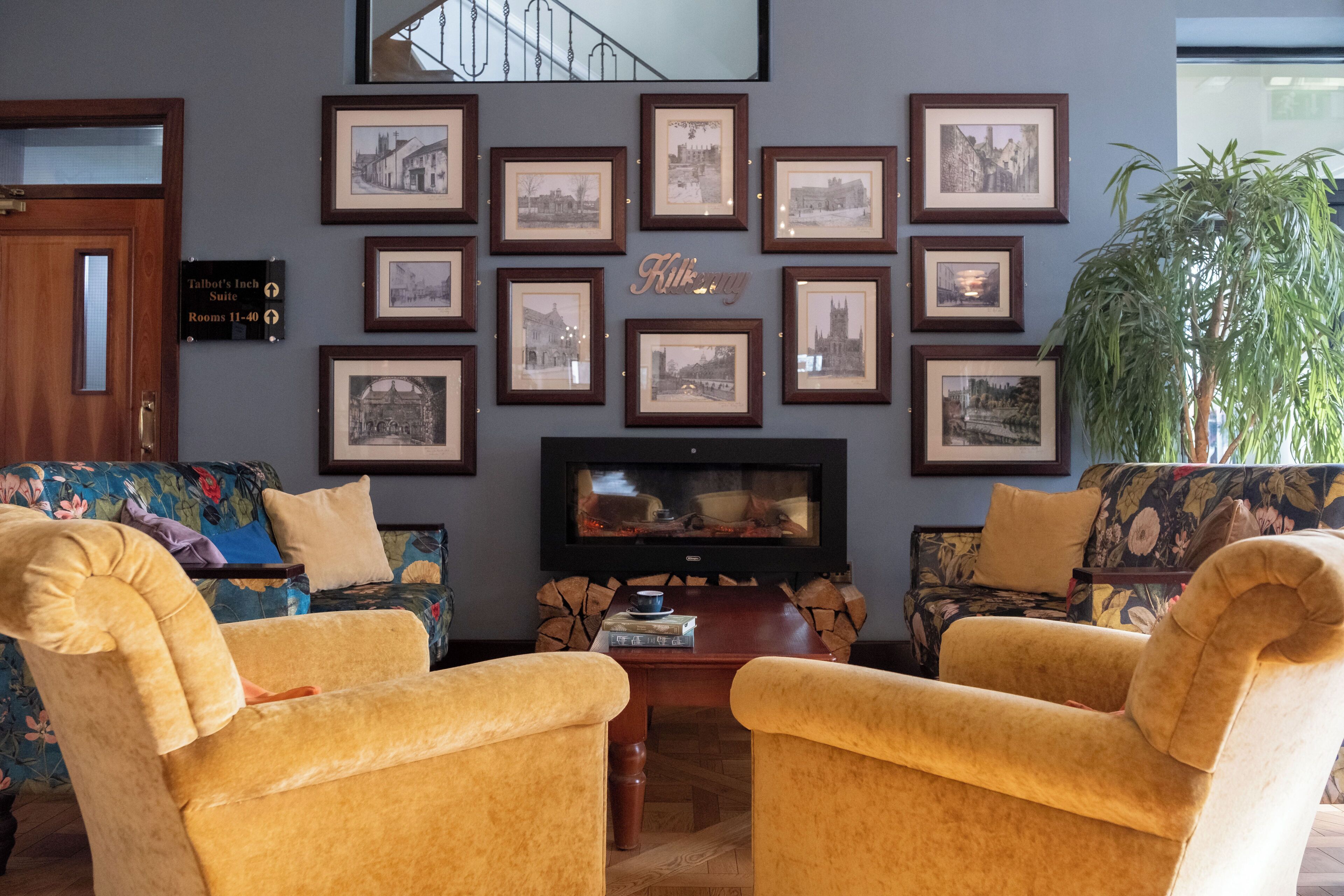 A living room with framed pictures, a television, and two yellow armchairs.