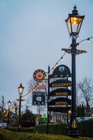 Un letrero que indica 'Kilkenny House Hotel' con un letrero de 'Takeaway' debajo, rodeado de faroles y follaje.