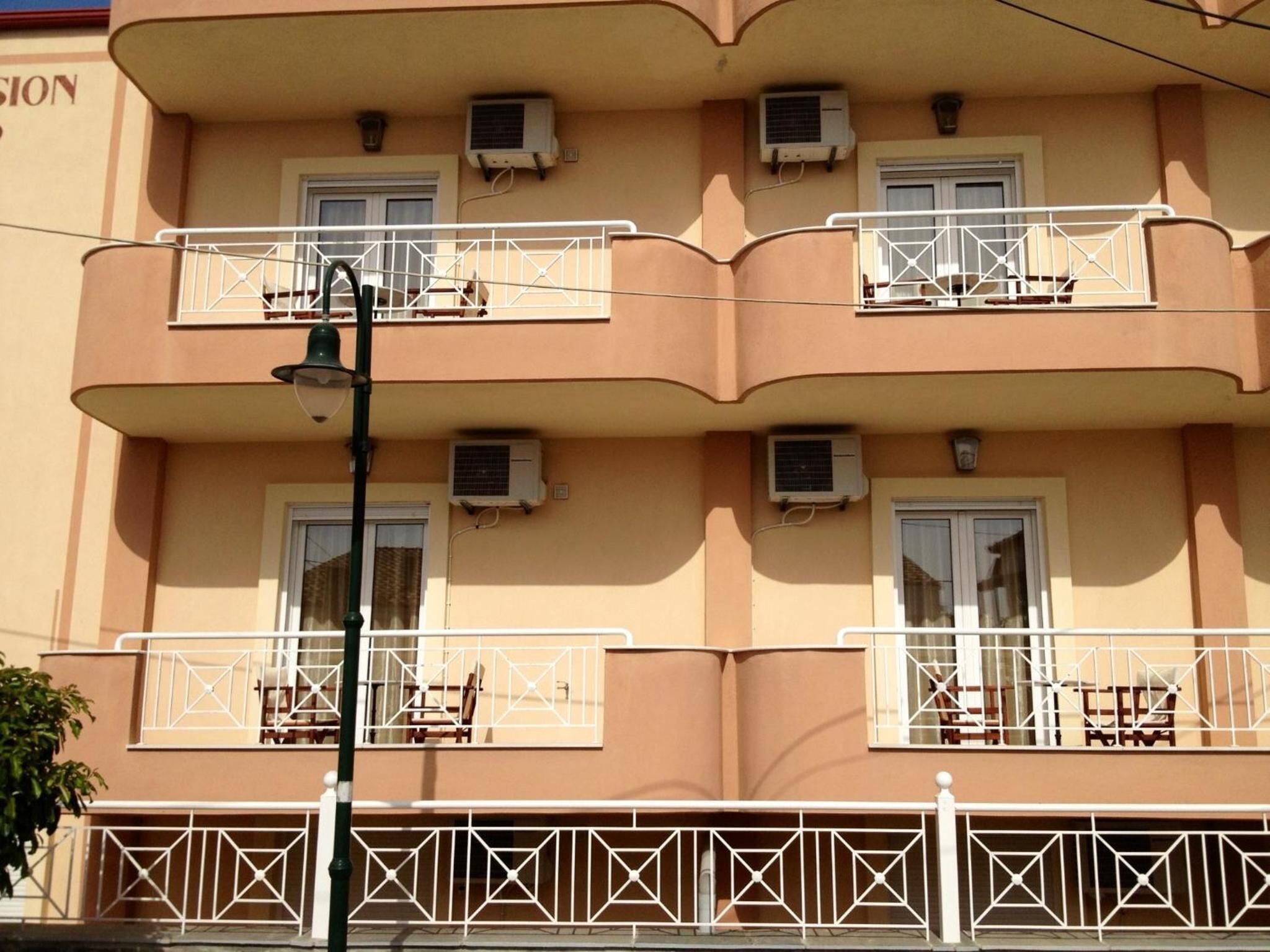 A multi-story building with balconies, air conditioning units, and a street lamp.