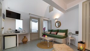 Un espacio habitable pequeño con kitchenette, un sofá con cojines, una mesita, un jarrón decorativo y un farol.